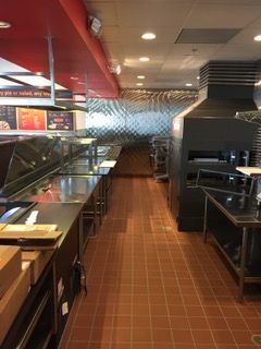 Restaurant kitchen interior with stainless steel countertops, red ceiling, and textured silver wall.