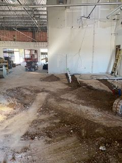 Interior view of a construction site. Dirt and trenches on floor, unfinished walls, and equipment.