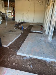 Construction site with exposed concrete slabs, plumbing, and wall framing.