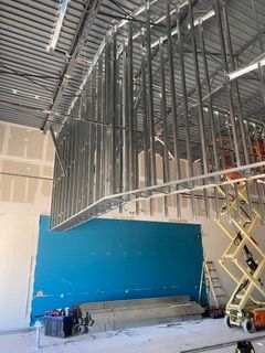 Steel framing for a suspended ceiling under construction, with a teal wall visible.
