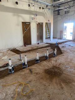 Construction site with exposed plumbing fixtures in a trench, doorways, and unfinished interior.