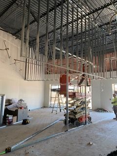 Construction site: metal framing for a ceiling. A lift and ladder present. Workers are nearby.