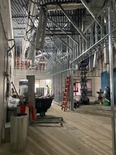 Interior of a building under construction, showing metal framing and exposed utilities.