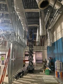Interior construction site with metal framework, ductwork, and a lift.