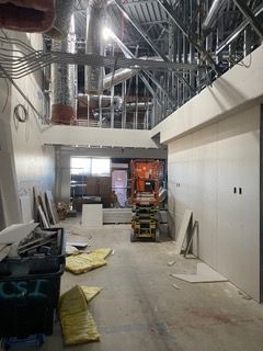 Interior construction site with exposed framing, drywall, and equipment.