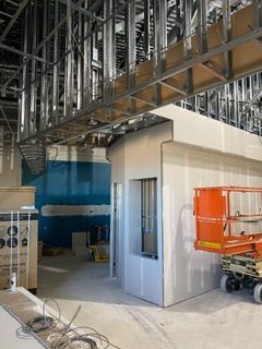Construction site with steel framing, drywall, and an orange lift. Interior view.
