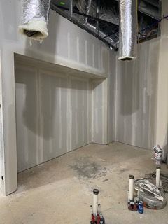 Interior of a room under construction with drywall and exposed pipes.