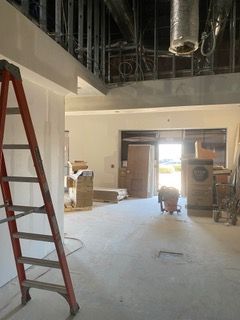 Interior construction site with a ladder, drywall, and open doorway.