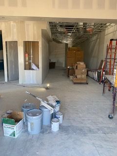Interior construction site with drywall, paint cans, and equipment, indicating a renovation in progress.