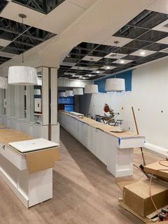 Interior construction: white counters and walls, checkered ceiling, blue accent, pendant lights, tools.