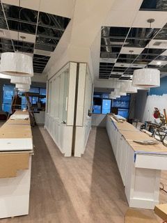 Interior of a commercial space under construction; white cabinetry, unfinished ceiling, and pendant lights.