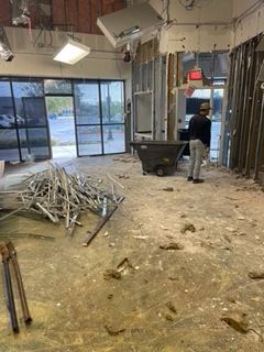 Interior demolition with debris, exposed studs, and a worker.