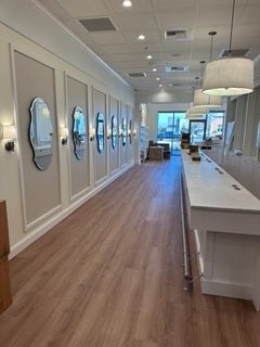 Long retail store hallway with wood floors and wall mirrors.