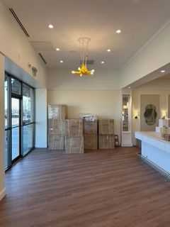 Empty retail space with boxes, glass windows, and a yellow chandelier.