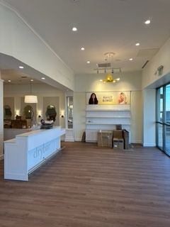 Interior of a hair salon with a white counter, empty shelves, and wood floors.