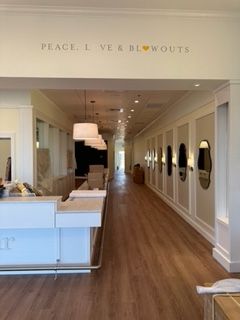 Interior of a salon with white walls, mirrors, and wooden floors. Text on top says 