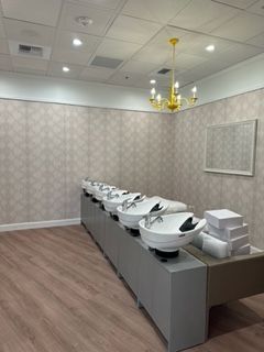 Hair salon with wash basins, decorative wallpaper, and a chandelier.