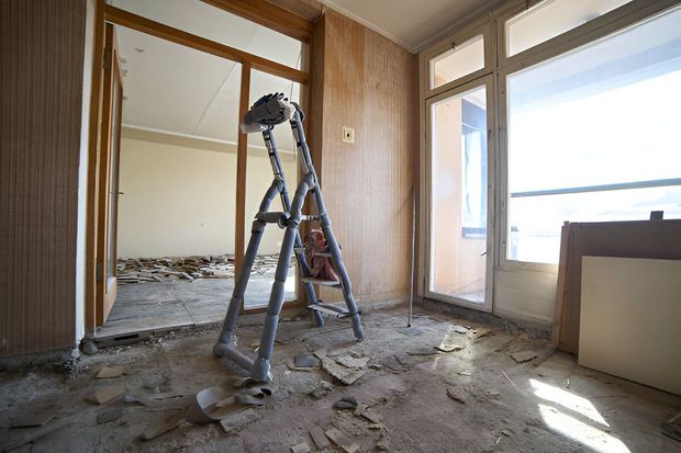 A ladder is sitting on the floor in an empty room.