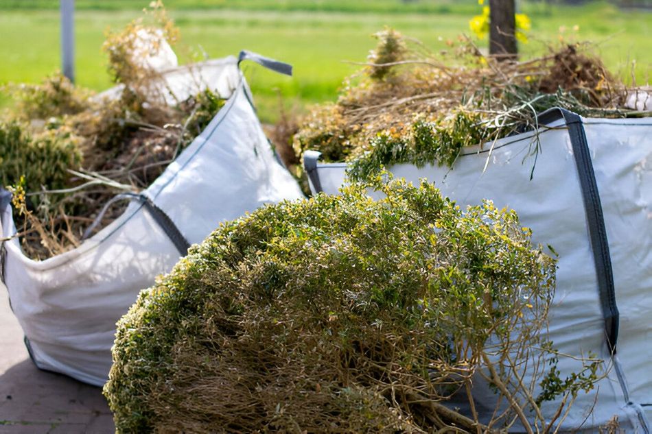 A bunch of bags filled with grass and branches are sitting on the ground.