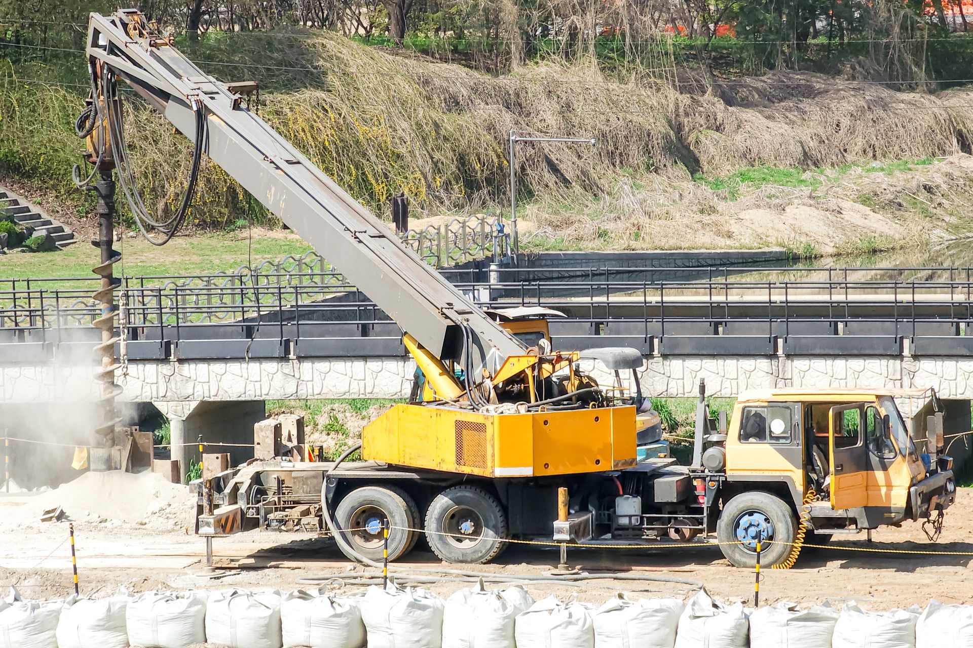 Truck mounted auger drilling hole in soil for fence post foundation construction equipment close up.