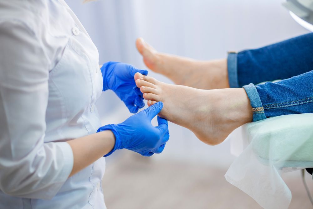 Podiatrist wearing blue gloves examines a patient 's foot — Podiatrist in Forster, NSW