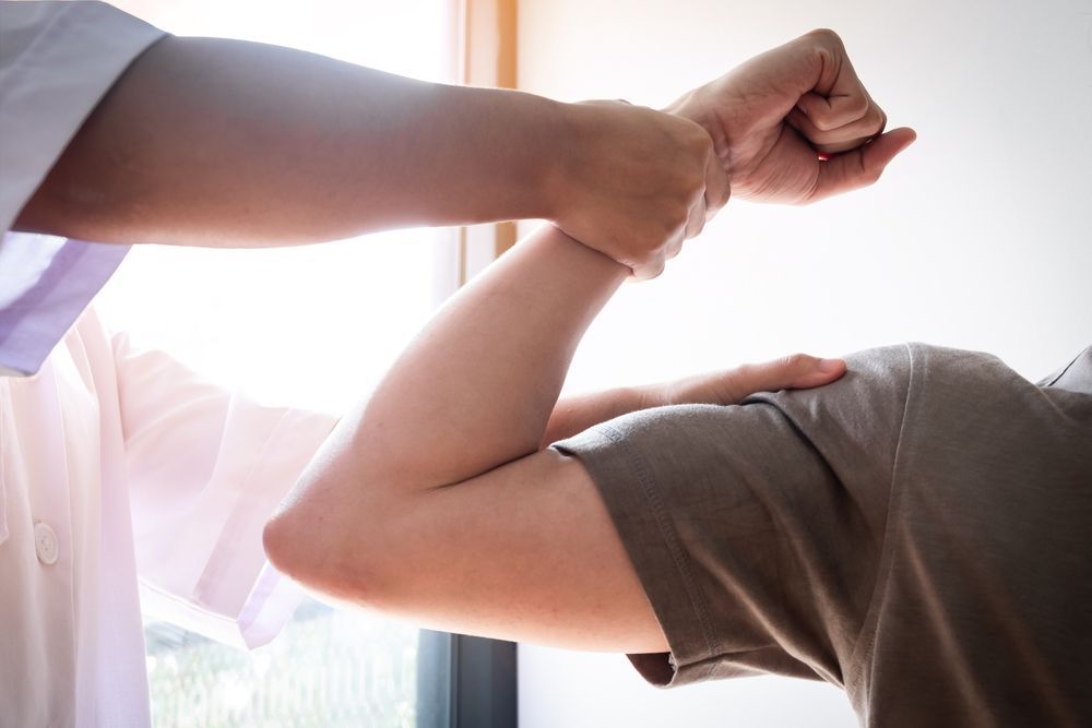 Therapist Assesses Male Patient's Bicep Muscle Strength — Exercise Therapy & Muscle Therapy in Forster, NSW