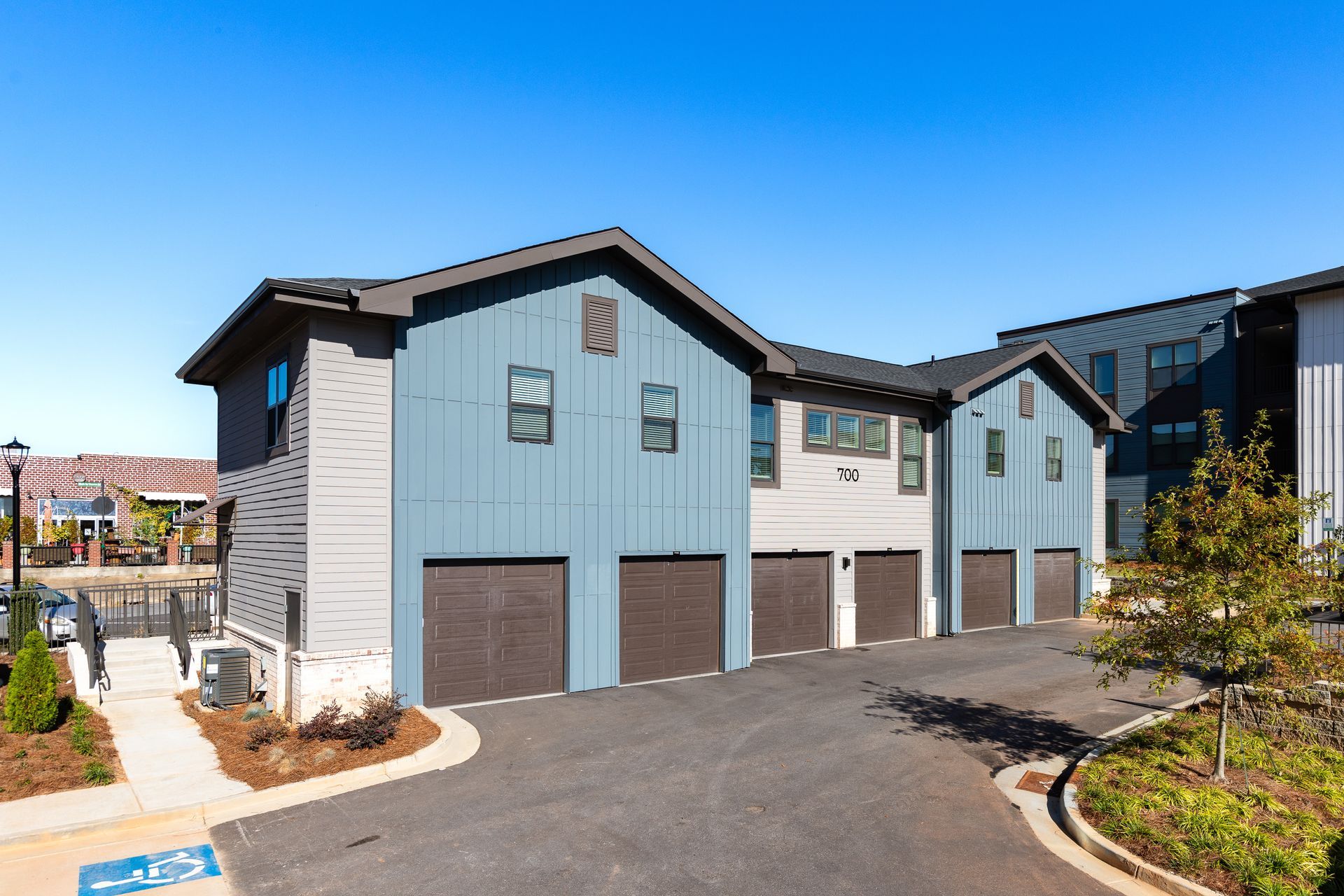 Modern two-story townhouses with gray siding and garages on a sunny residential street