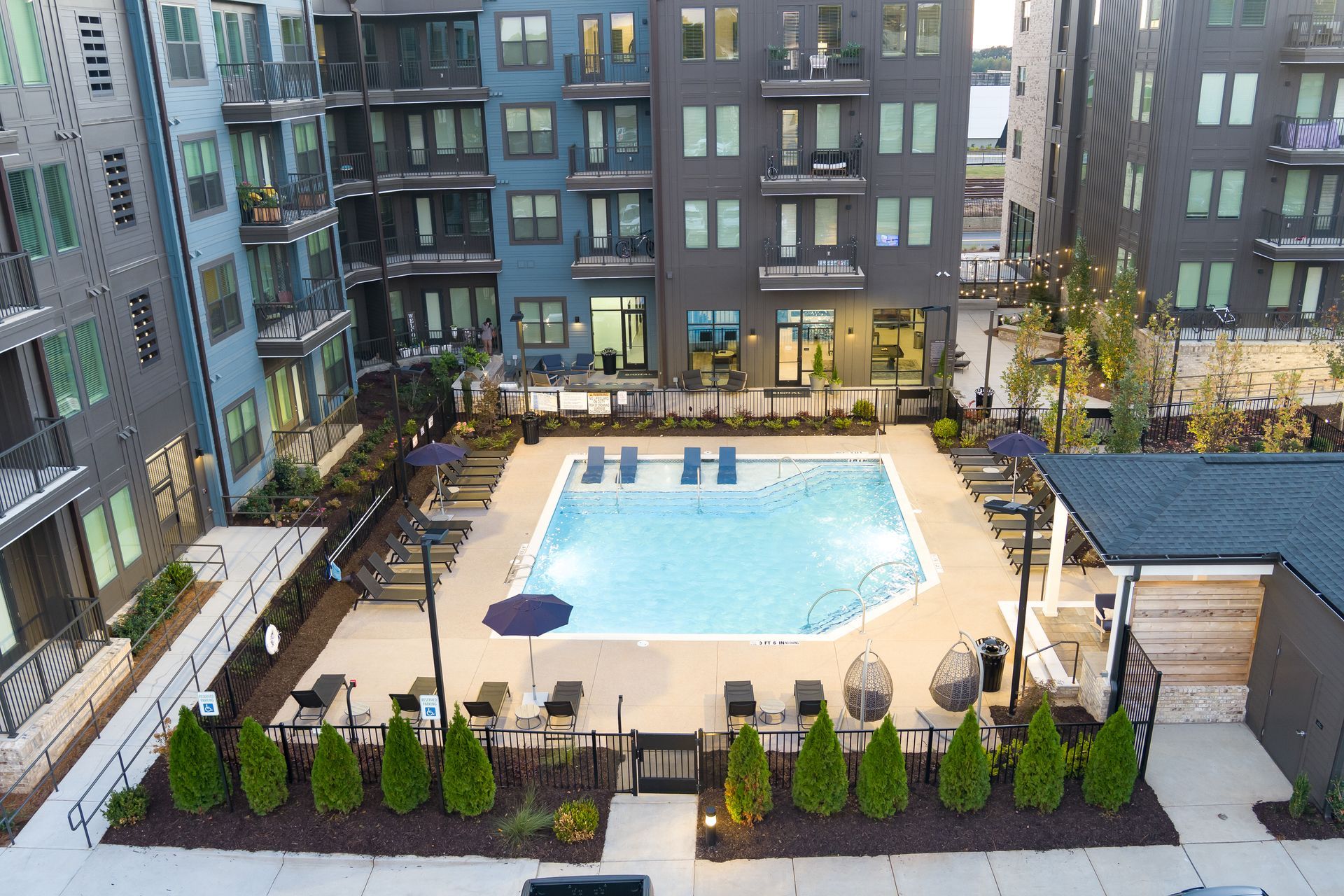 Rooftop swimming pool surrounded by apartment buildings and lounge chairs.