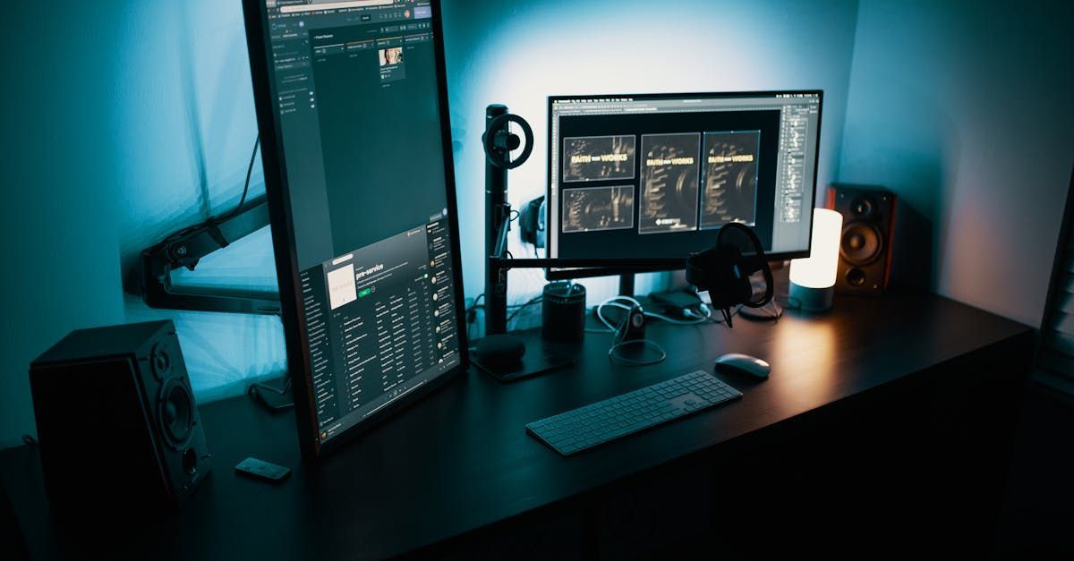 A computer desk with two monitors , a keyboard , and a microphone.