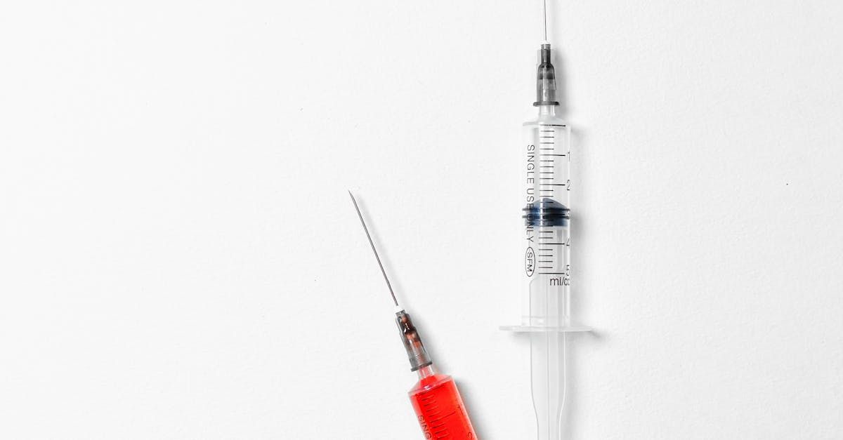 Two syringes are sitting next to each other on a white surface.