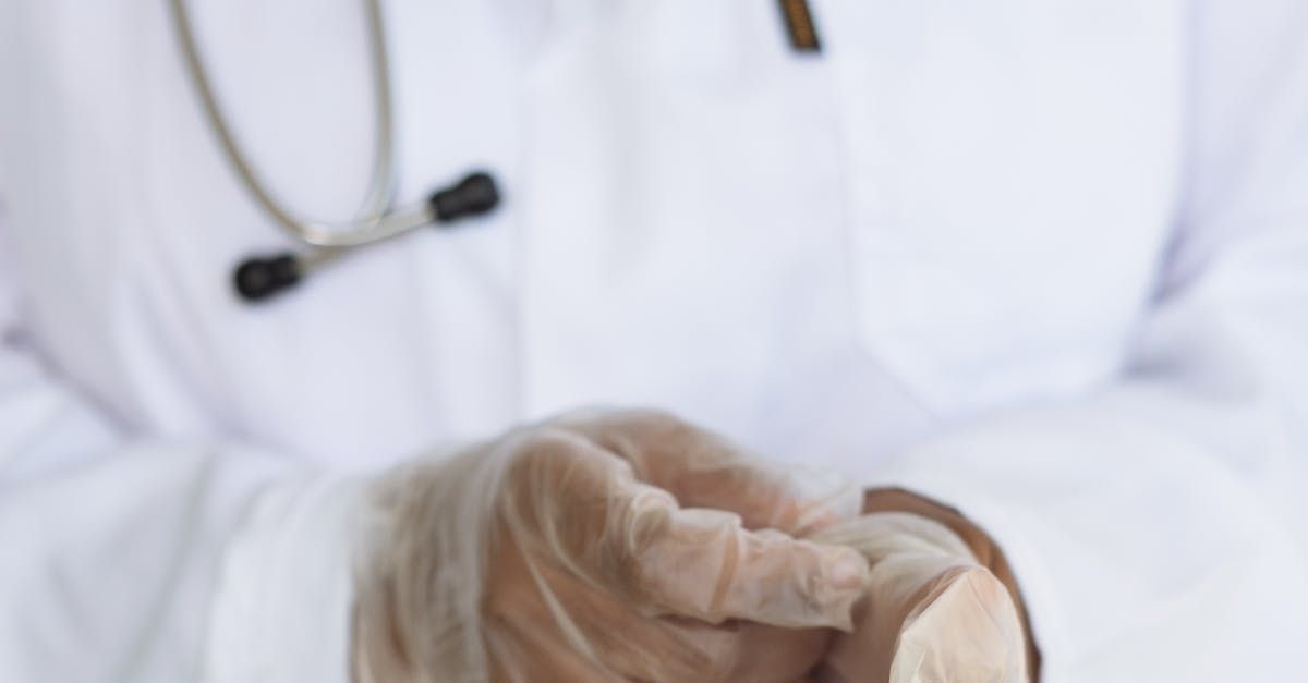 A close up of a doctor wearing gloves and a stethoscope.