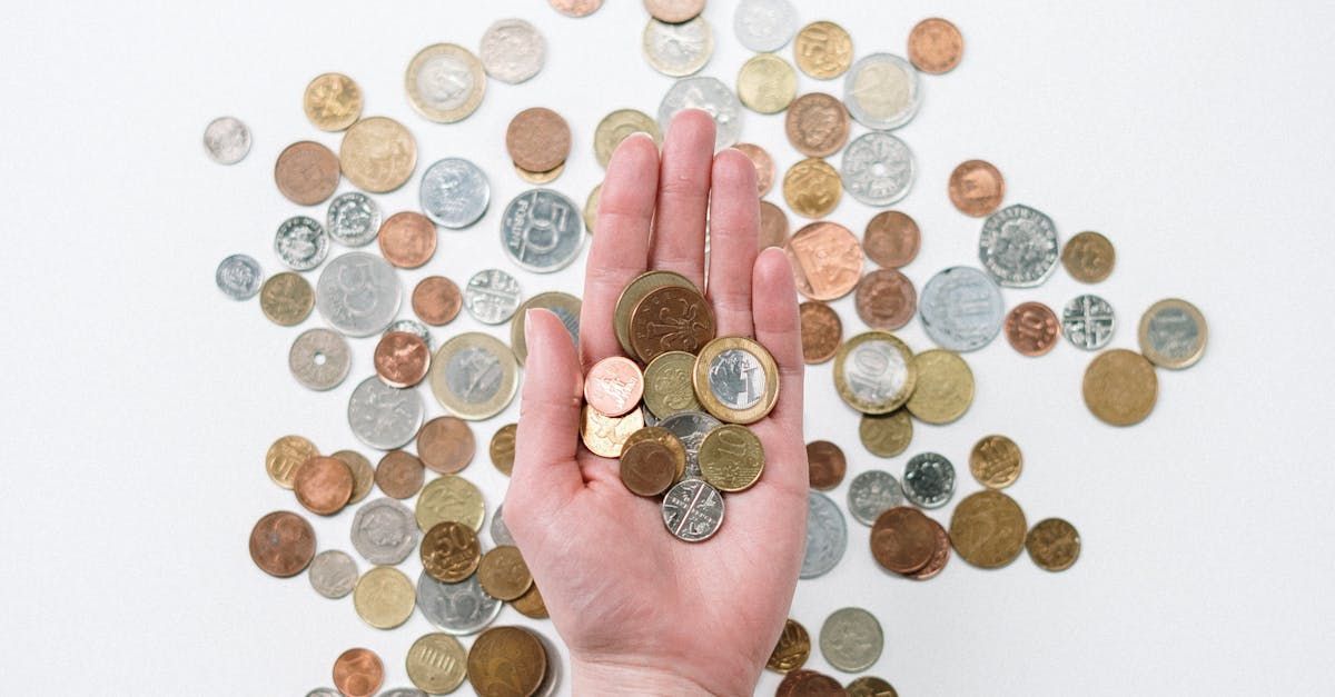 A person is holding a handful of coins in front of a pile of coins.