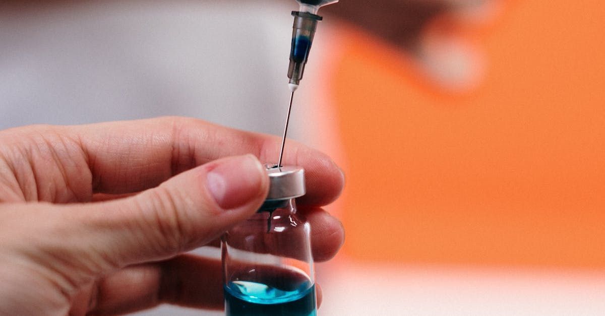 A person is pouring a vaccine into a bottle.