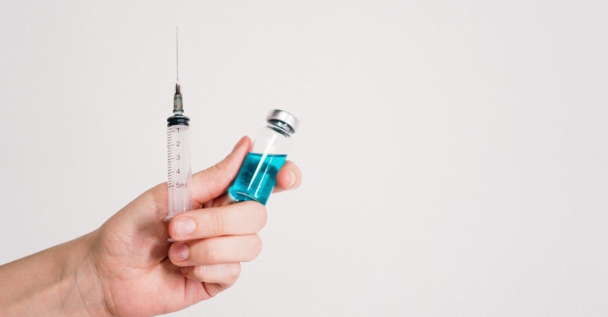 A person is holding a syringe and a bottle of vaccine.