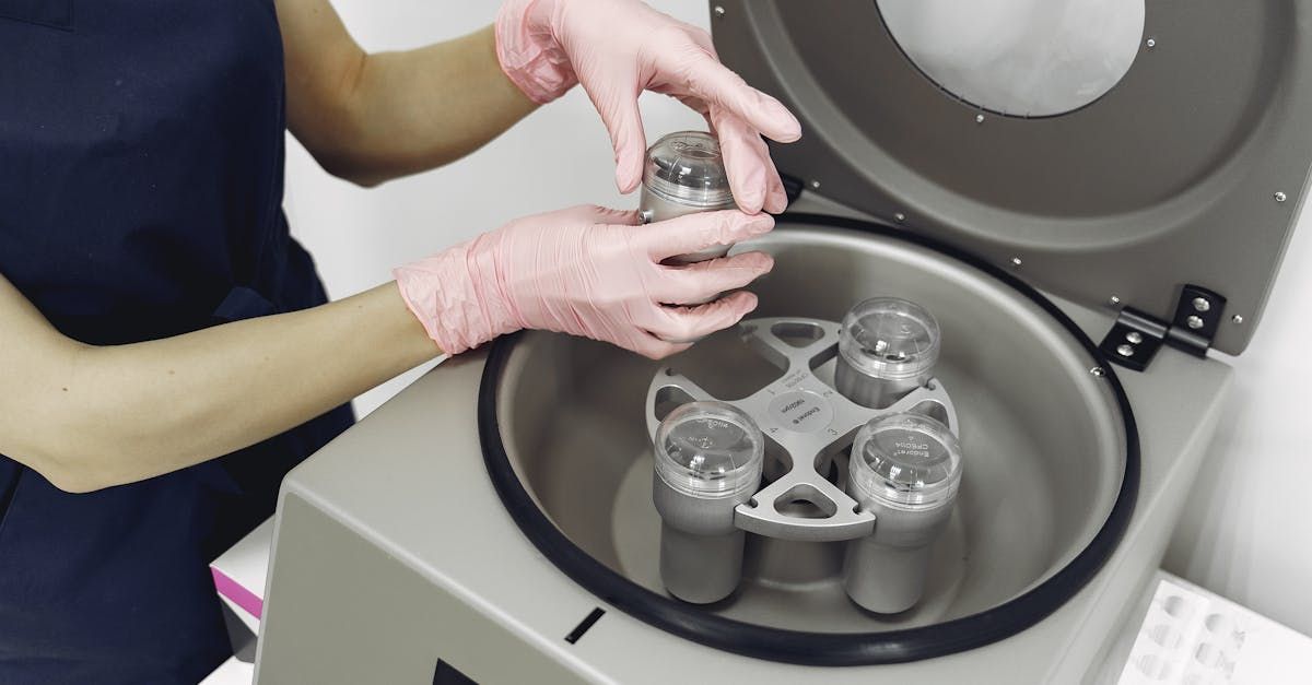 A person is putting a bottle into a centrifuge.