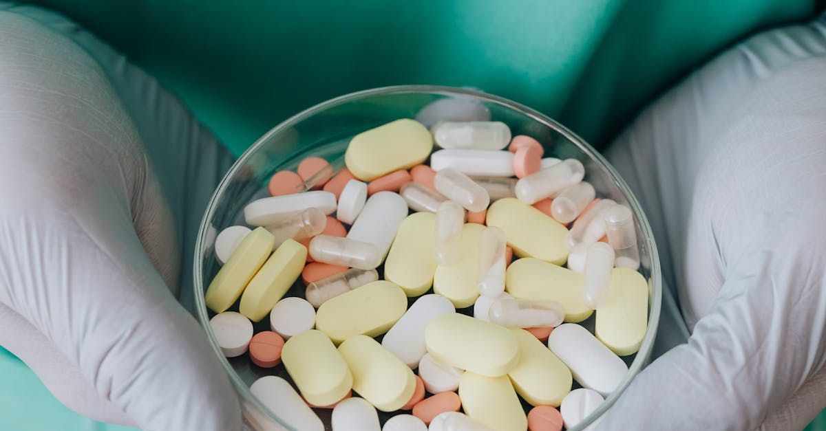 A person is holding a petri dish filled with pills.