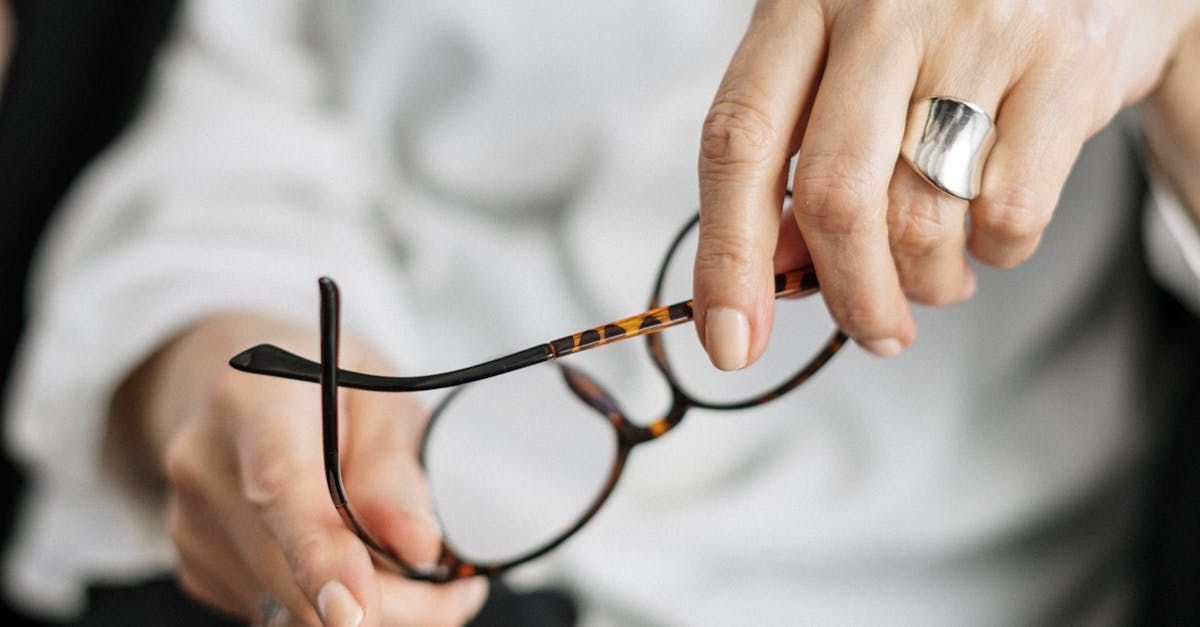 A woman is holding a pair of glasses in her hands.