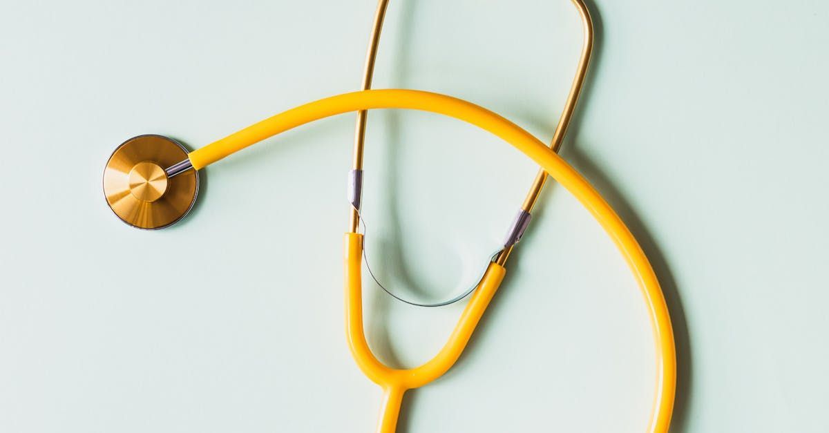 A yellow stethoscope is sitting on a white surface.