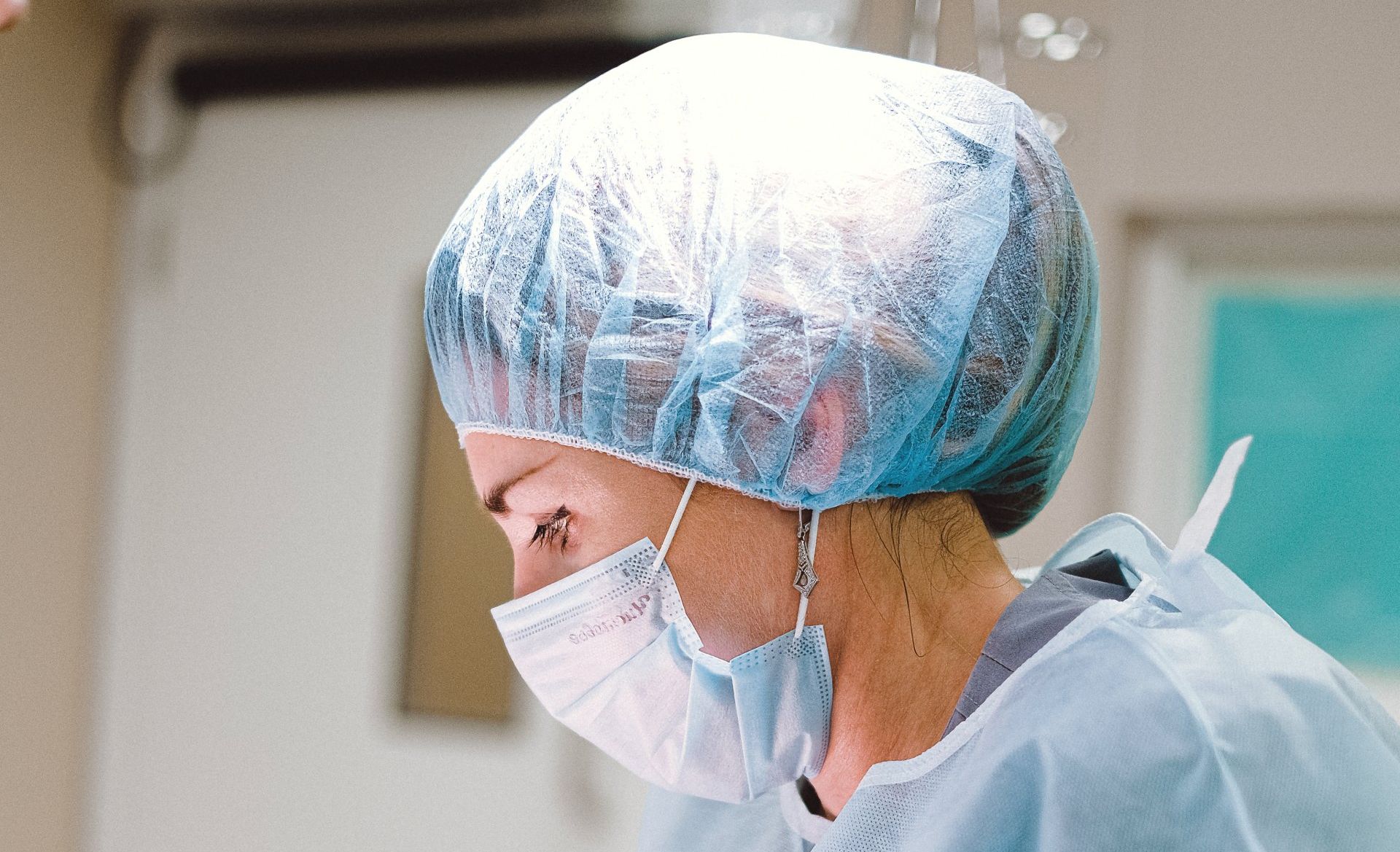 A close up of a surgeon wearing a mask and surgical cap.