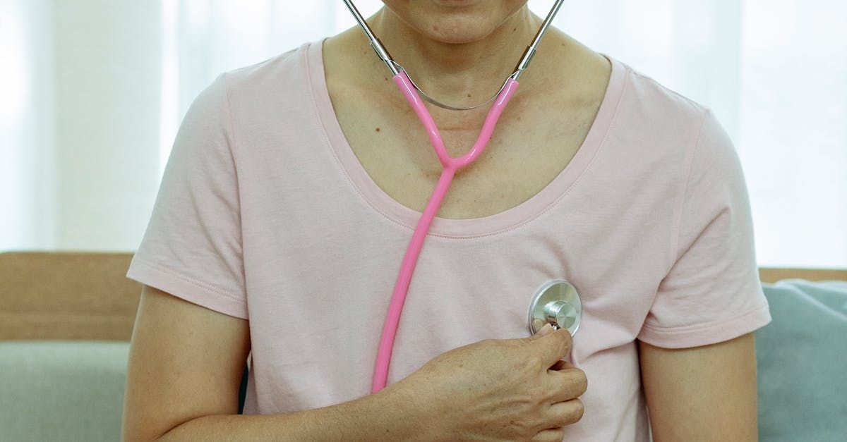 An elderly woman is listening to her heart with a stethoscope.