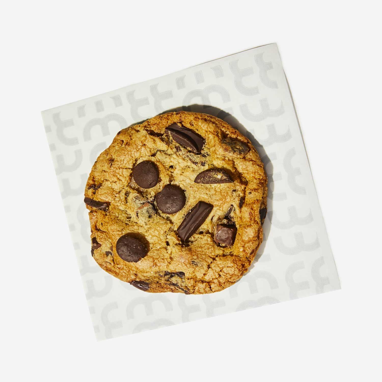A chocolate chip cookie is on a napkin that says coffee