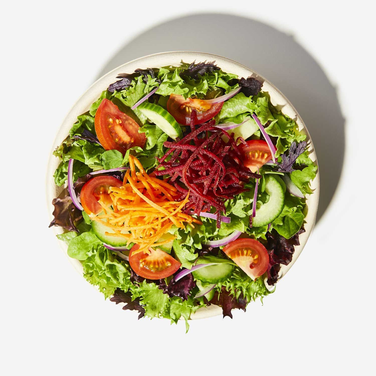 A salad with lettuce tomatoes carrots and beets on a white plate