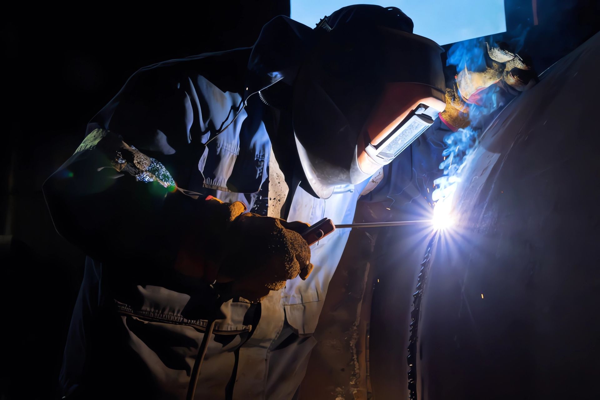 A man wearing a welding mask is welding a piece of metal — Mayric Engineering in Forster, NSW