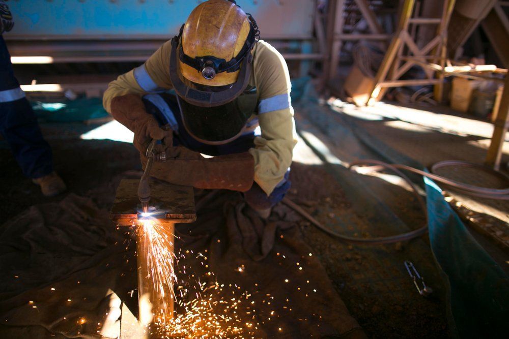 A Man Is Cutting a Piece of Metal with A Torch — Mayric Engineering in Old Bar, NSW