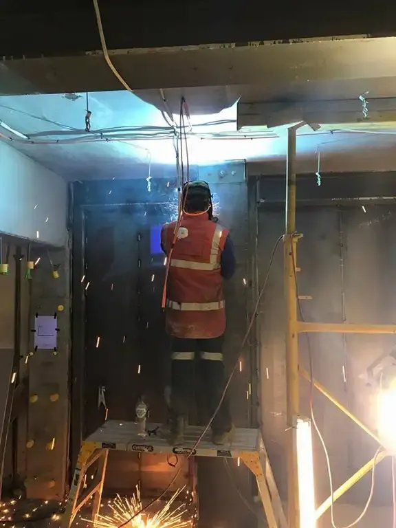 A Man in A Red Vest Is Welding in A Room — Mayric Engineering in Taree, NSW