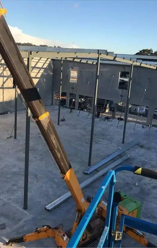 A Crane Is Sitting on The Ground in Front of A Building Under Construction — Mayric Engineering in Old Bar, NSW