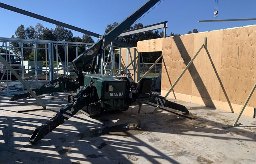 Spider Crane is Sitting on the Ground in Front of a Building Under Construction — Mayric Engineering in Taree, NSW