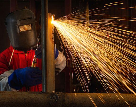 Man Wearing a Welding Mask is Cutting a Piece of Metal — Mayric Engineering in Taree, NSW