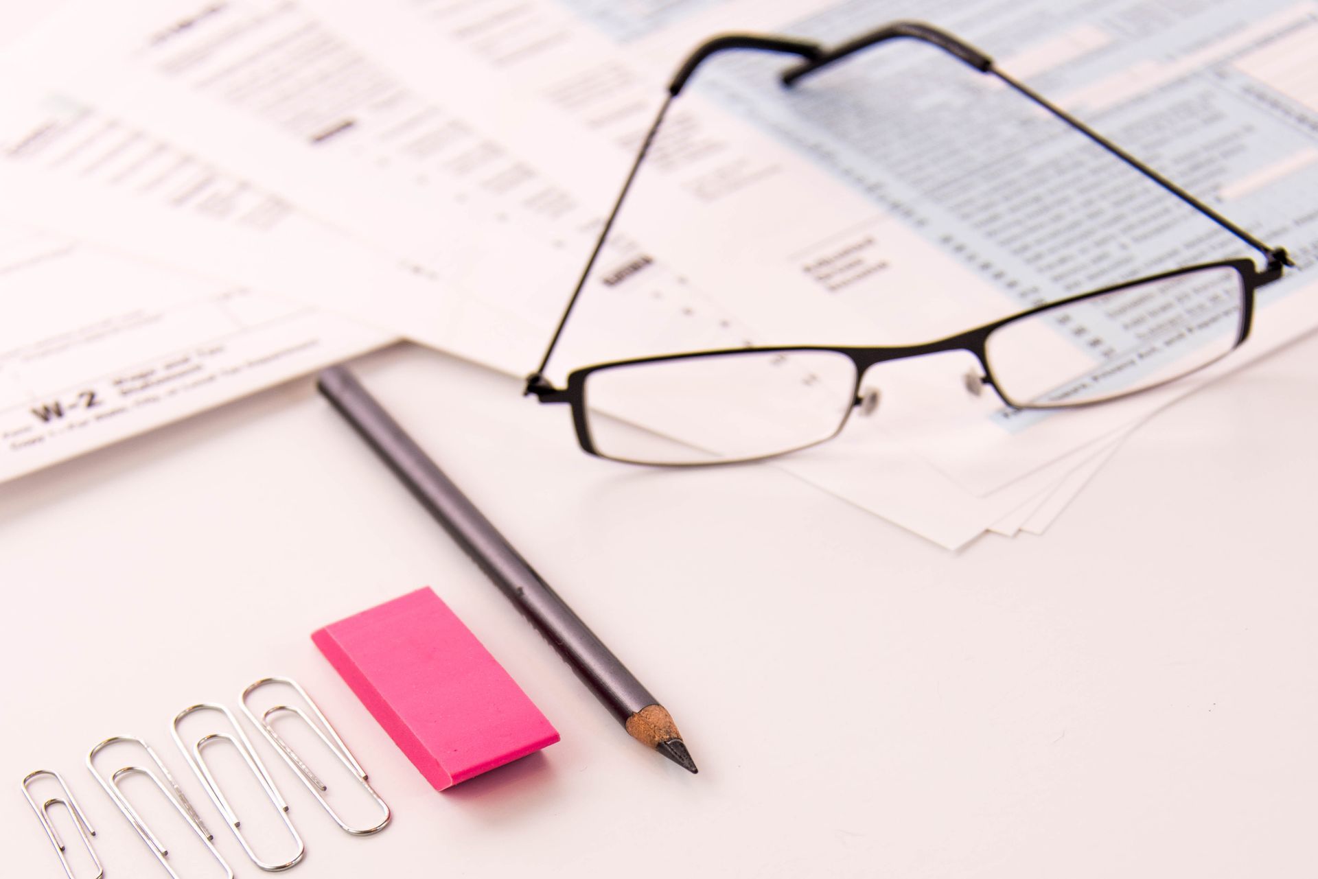 A pair of glasses sits on top of a piece of paper