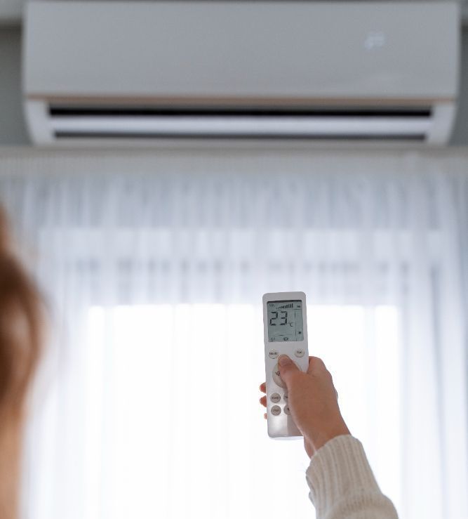 Uma pessoa está segurando um controle remoto na frente de um ar condicionado.-Pousada-Casa-Flor